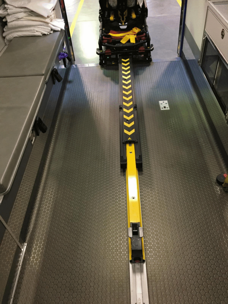 Powered cot fastener system helps boost safety by supporting the cot throughout loading and unloading, eliminates the need to steer the cot into and out of the ambulance